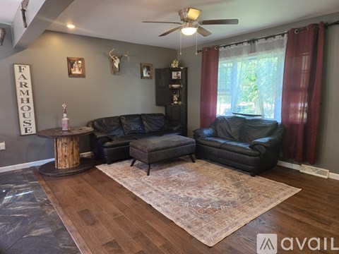 A living room with a black leather couch and a wooden coffee table.