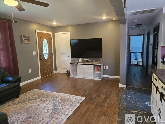 A living room with a black couch and a flat screen TV mounted on the wall.