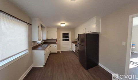 A kitchen with white cabinets and a black fridge.