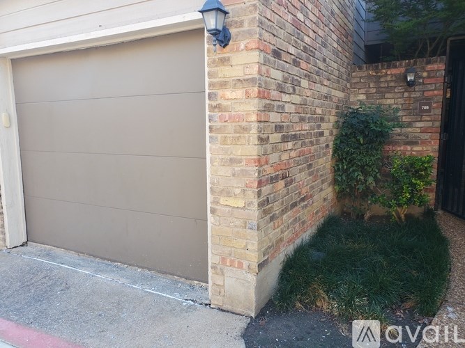 A garage door is closed and the wall is made of bricks.