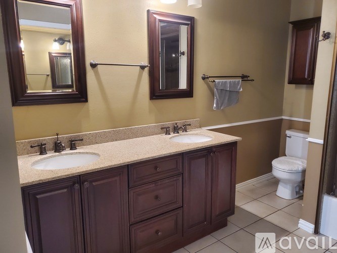 A bathroom with a double sink vanity and a toilet.