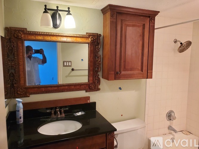 A man is taking a picture of a bathroom with a mirror.