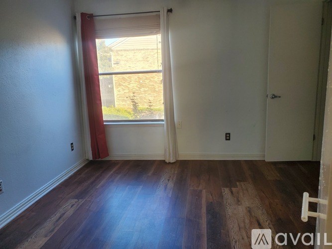 A room with wooden floors and a window with a view of a building outside.