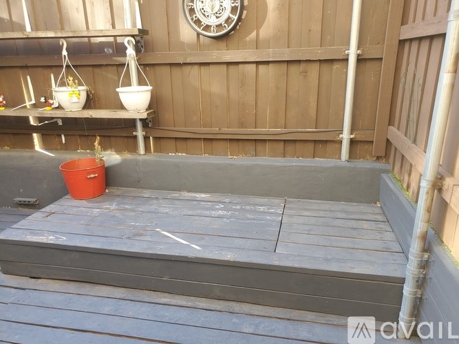 A red bucket is sitting on a grey wooden platform.