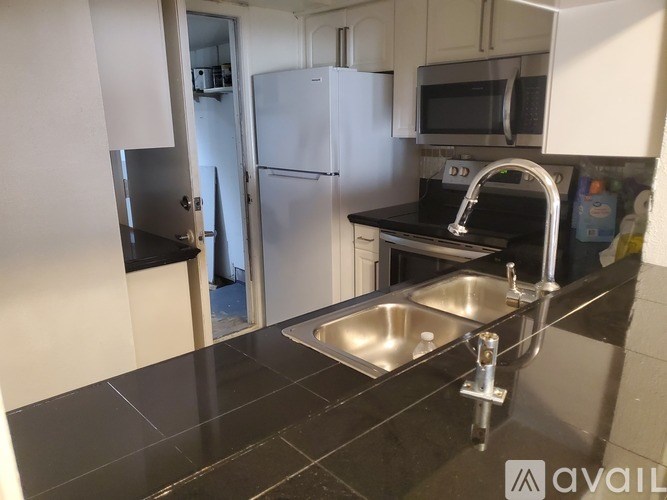A kitchen with a black countertop and stainless steel appliances.