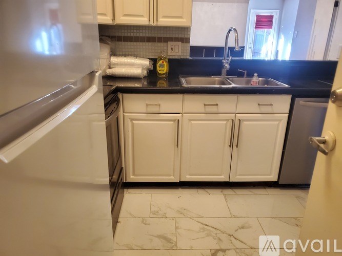 A kitchen with white cabinets and a black countertop.