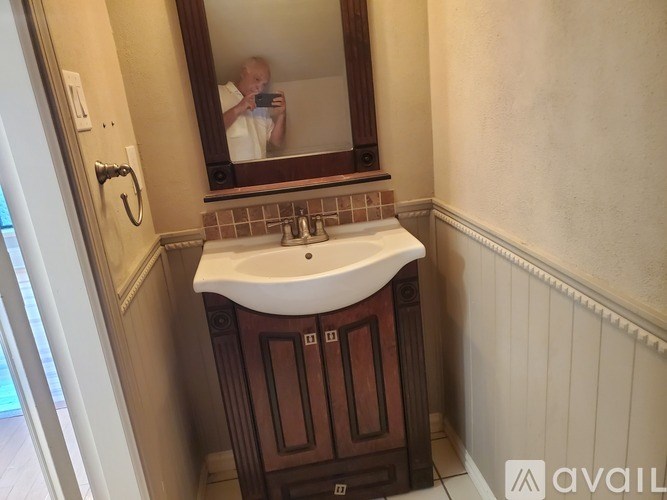 A man is taking a picture of a bathroom sink in a mirror.