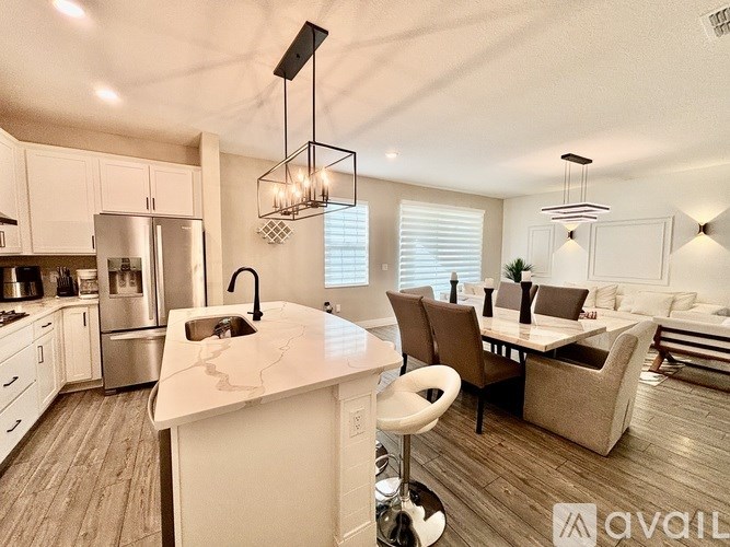 A modern kitchen with a large island and pendant lights.
