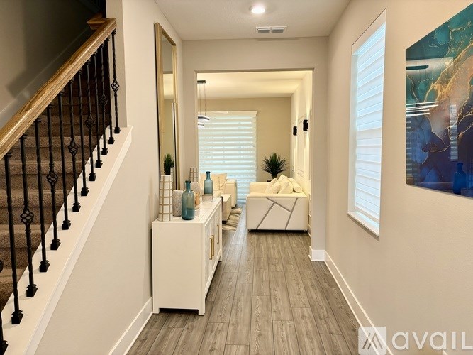 A hallway with a staircase on the left and a couch on the right.