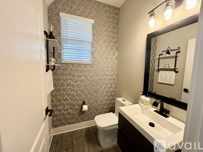 A bathroom with a toilet, sink, and mirror.