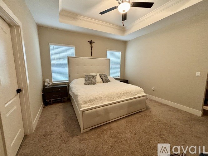 A bedroom with a bed, nightstand, and a ceiling fan.