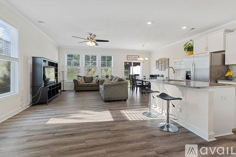 A modern kitchen with a bar area and a living room with a couch and a TV.