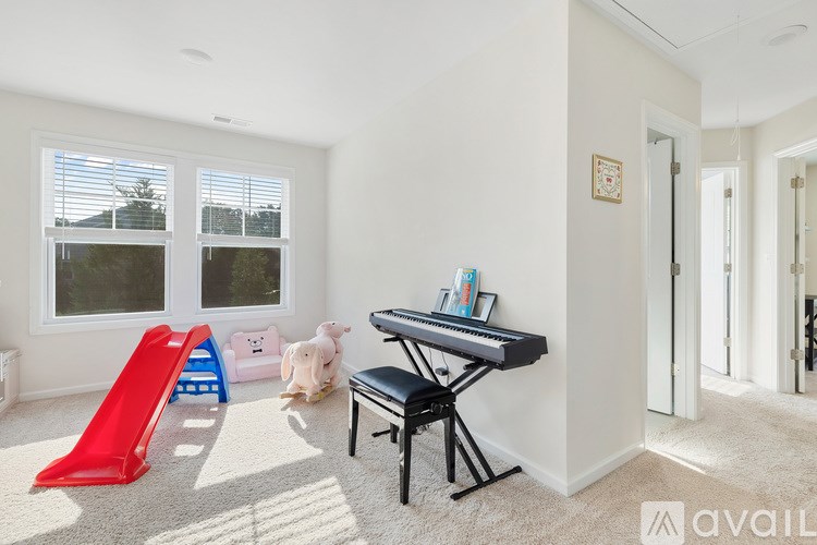 A room with a red slide, a piano, and a teddy bear.