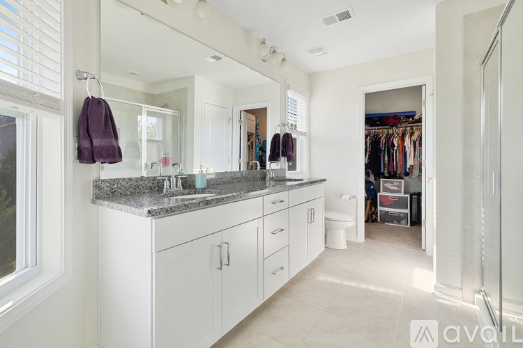 A bathroom with a marble countertop and white cabinets.