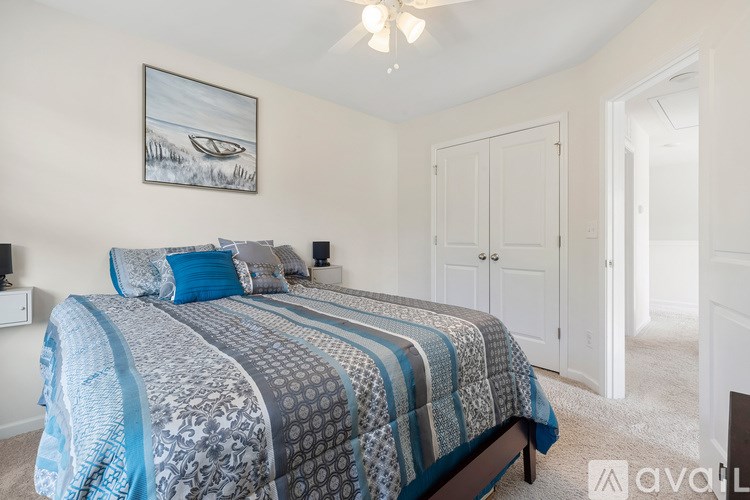 A bedroom with a bed, a painting, and a chandelier.