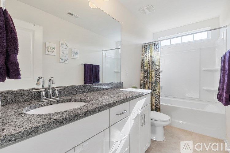 A bathroom with a granite countertop and white cabinets.
