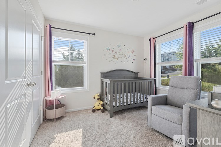 A baby room with a crib, chair, and teddy bear.