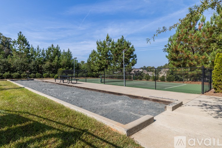 A tennis court surrounded by trees and a fence.