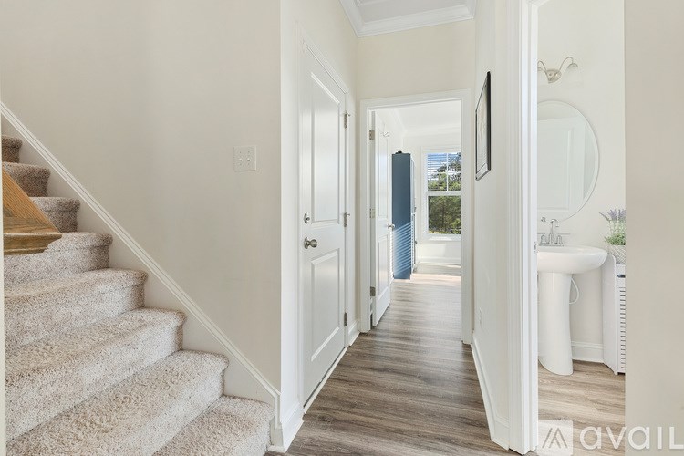 A hallway with a staircase on the left and a bathroom on the right.