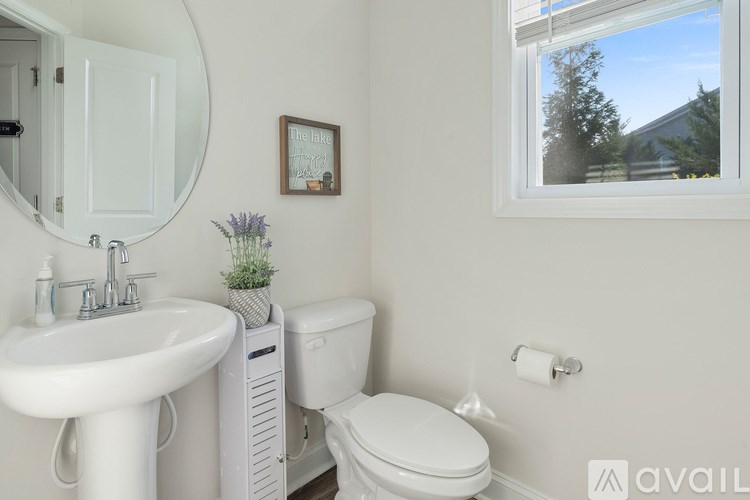 A white bathroom with a toilet, sink, and mirror.
