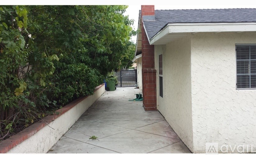 A white house with a red brick chimney and a green trash can.