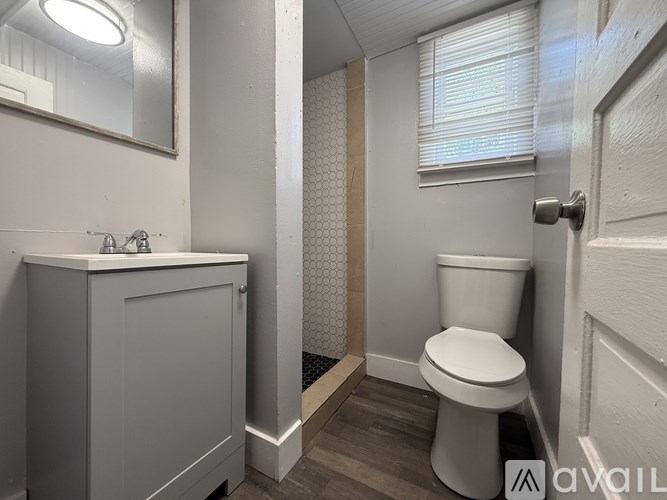 A white toilet sits in a small bathroom with a white sink and a mirror.