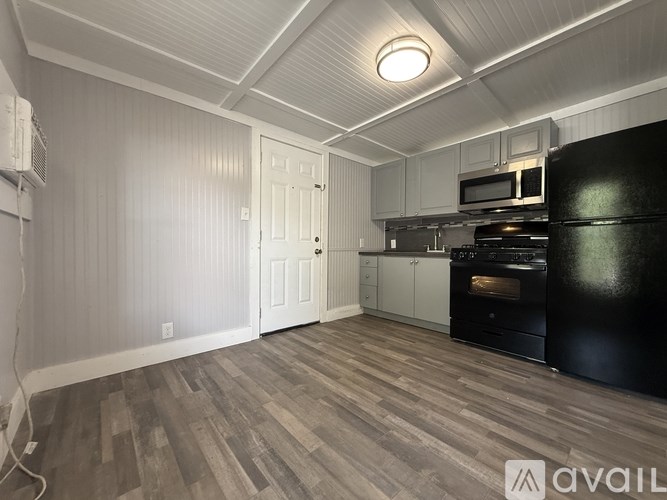 A kitchen area with a black oven and wooden flooring.