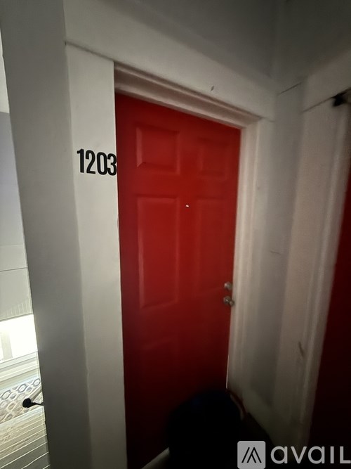 A red door with the number 1203 on the wall above it.