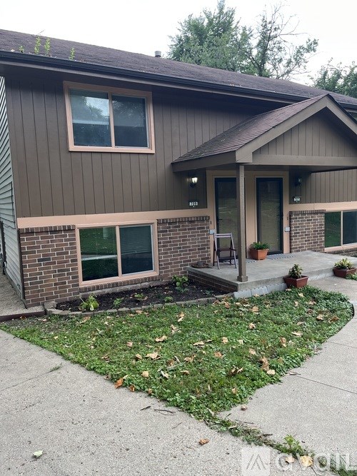A house with a brown siding and a grey roof.