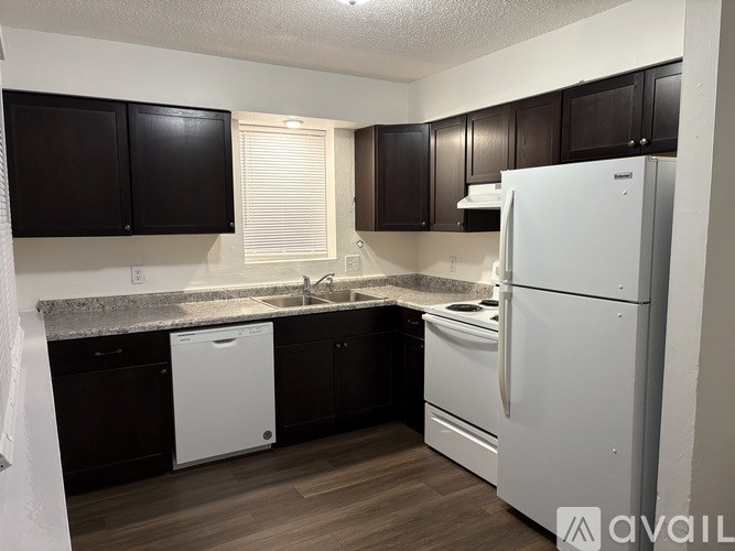 A kitchen with black cabinets and white appliances.