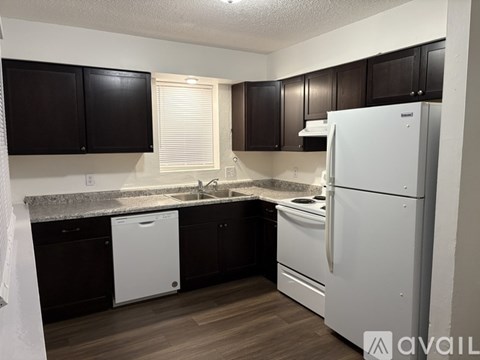 A kitchen with black cabinets and white appliances.