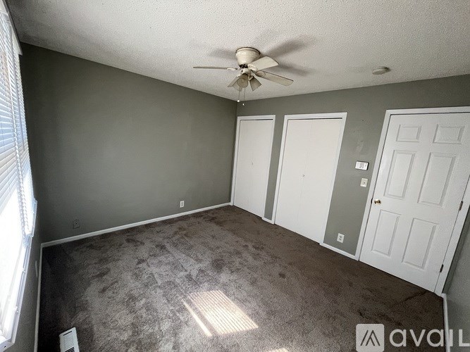 A room with a ceiling fan and three doors.