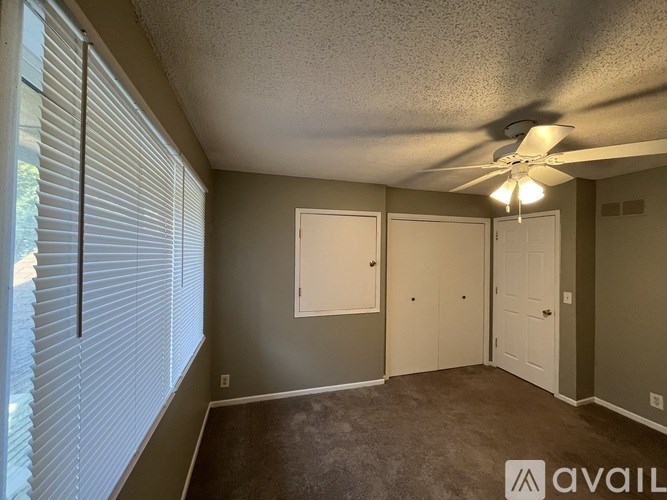 A room with a ceiling fan and three doors.