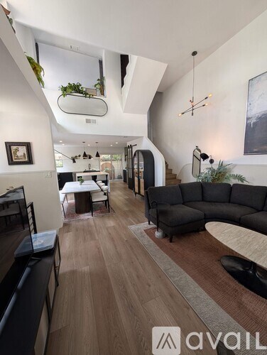 A living room with a black sofa and wooden flooring.