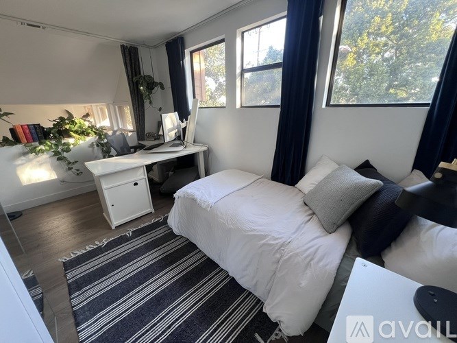 A bedroom with a bed, desk, and window.