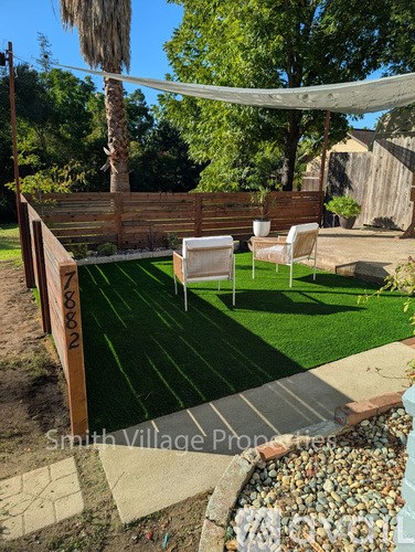 A backyard with a wooden fence and a green lawn.