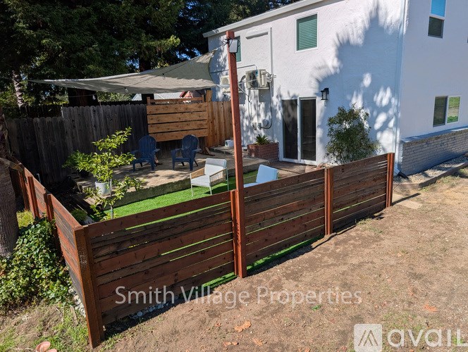A white house with a wooden fence and a sign that says Smith Village Properties.
