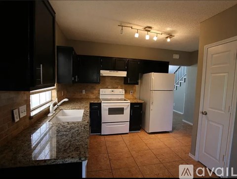 A kitchen with black cabinets and a white refrigerator.