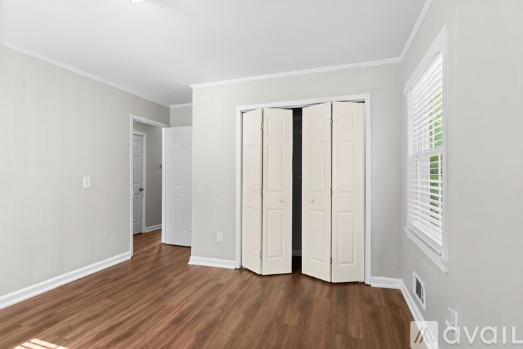 A room with a white wall and a wooden floor with a white door and a white wardrobe.