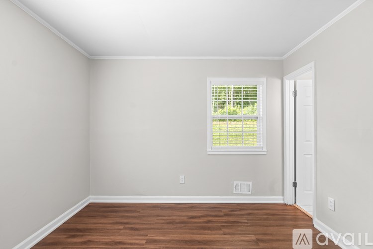 A room with a window and wooden flooring.