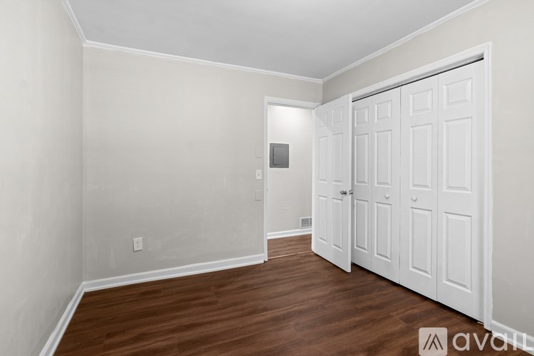 A room with a white door and wooden flooring.