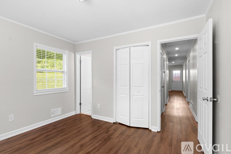A long hallway with white doors and a window with blinds.