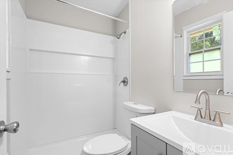 A white bathroom with a toilet, sink, and mirror.