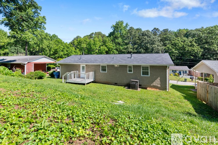 A house with a grey roof is surrounded by greenery.