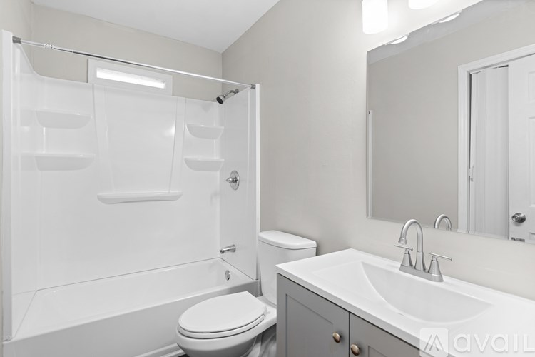 A white bathroom with a toilet, sink, and shower.