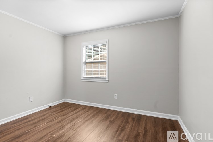 A room with a window and wooden flooring.