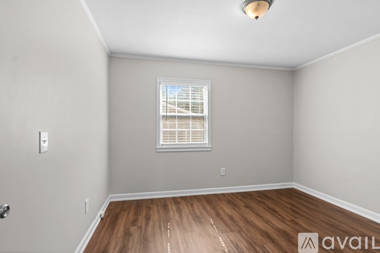A room with wooden flooring and a window with blinds.