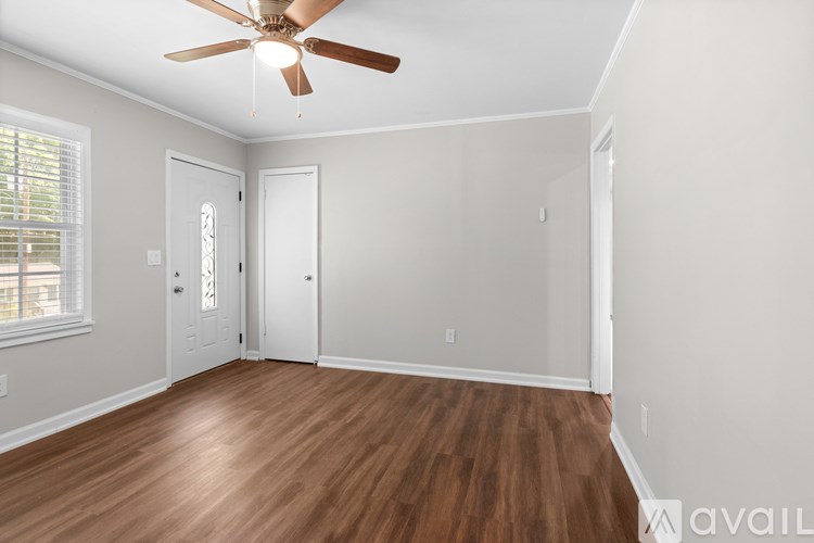 A room with a ceiling fan and wooden flooring.