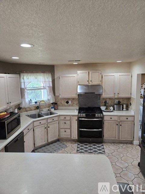 A kitchen with a black stove top oven and white cabinets.