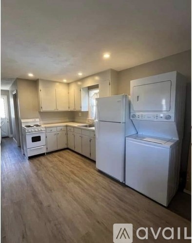 A kitchen with white appliances and wooden floors.